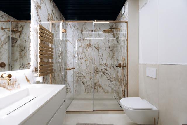 A luxurious bathroom featuring elegant marble walls and a modern shower area