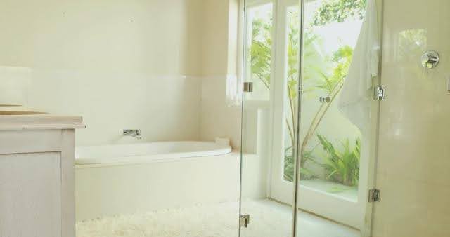 A spacious villa bathroom featuring a modern sink, elegant tiles, and a large mirror above the vanity