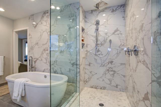 A stylish bathroom with polished marble walls and a sleek glass shower, creating a sophisticated atmosphere