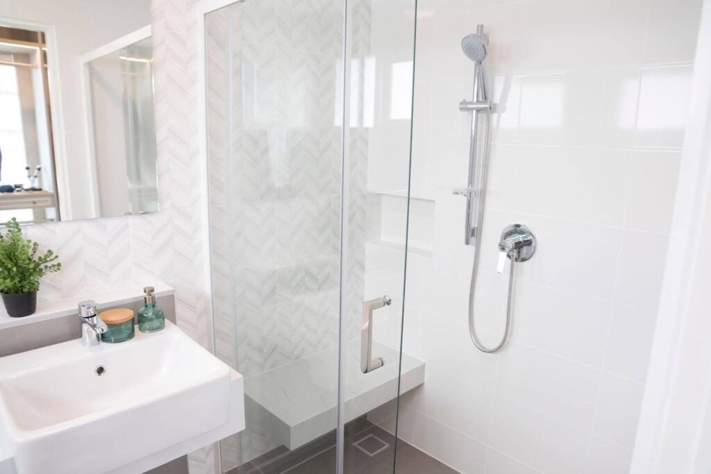 A clean bathroom featuring a modern shower and a sleek sink with neutral-colored tiles and bright lighting