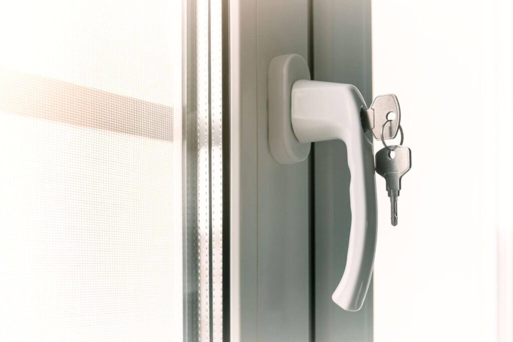 Close up of a white window handle with keys inserted