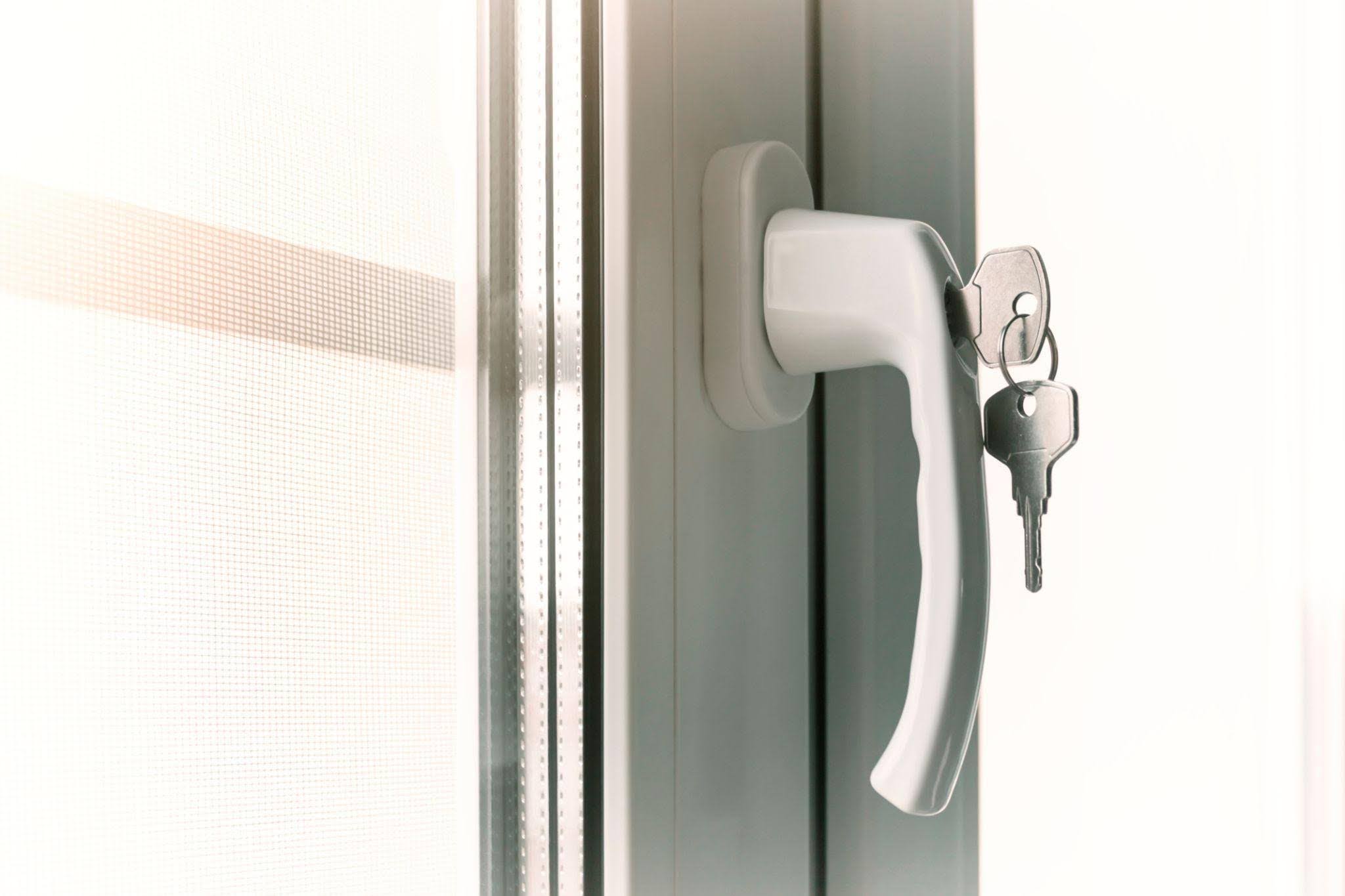 Close up of a white window handle with keys inserted