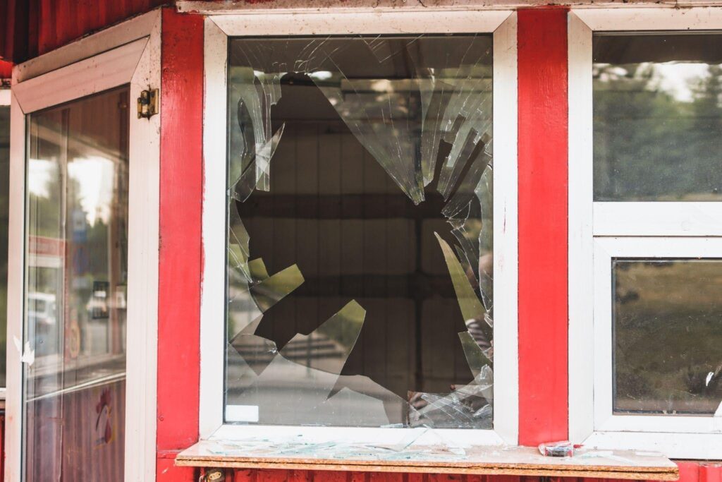 A small red and white building has a shattered front