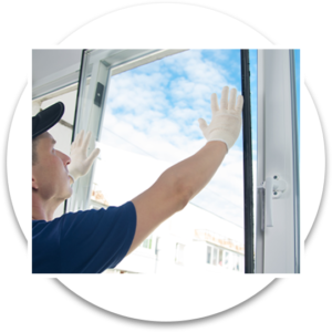 A man in gloves and a hat cleaning a window with a squeegee.