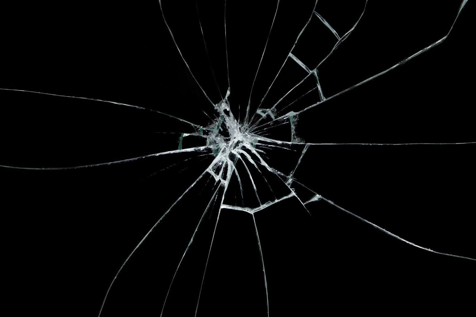 Fragments of broken glass on a dark backdrop showcasing intricate patterns and light