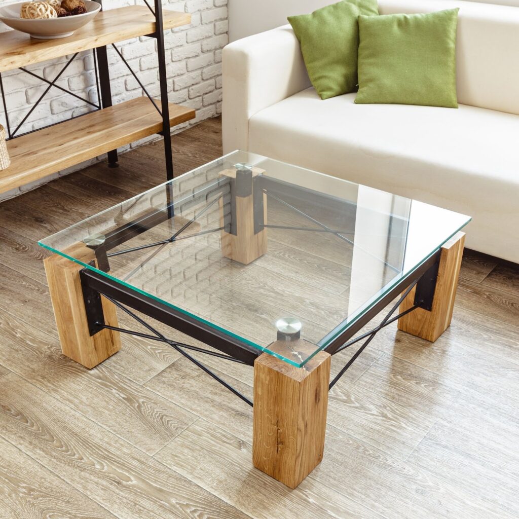Modern living room with a glass coffee table, wooden shelves, and a white sofa with green cushions.
