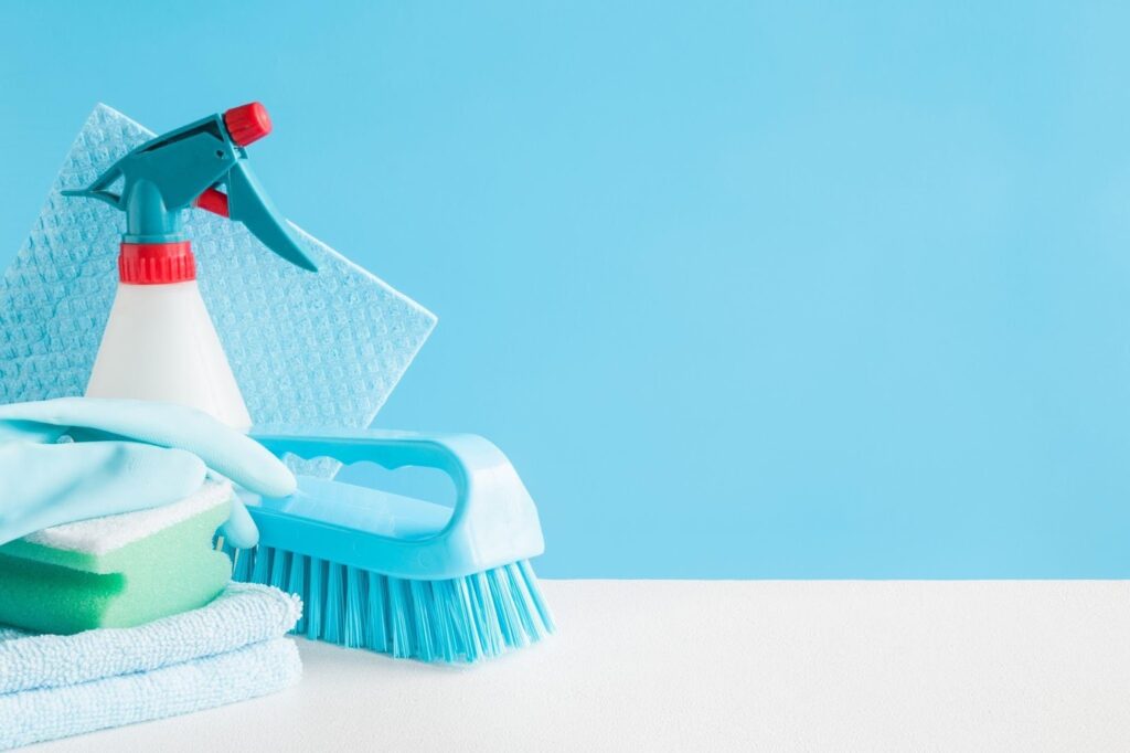 Cleaning supplies including spray bottles and sponges arranged on a blue background