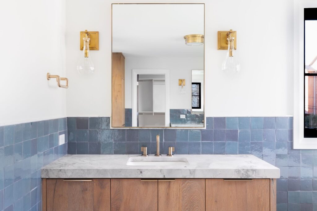 A bathroom with blue tile and wood cabinets. Custom and standard mirrors available for replacement.