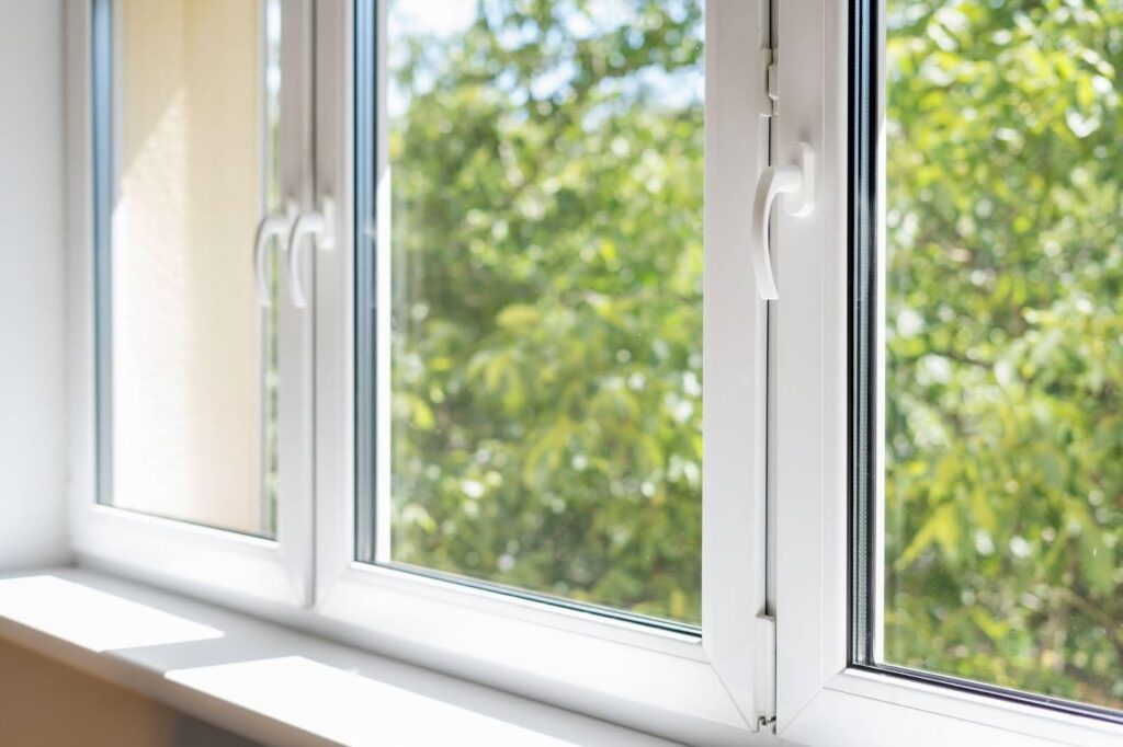 A white window framed by a lush green tree
