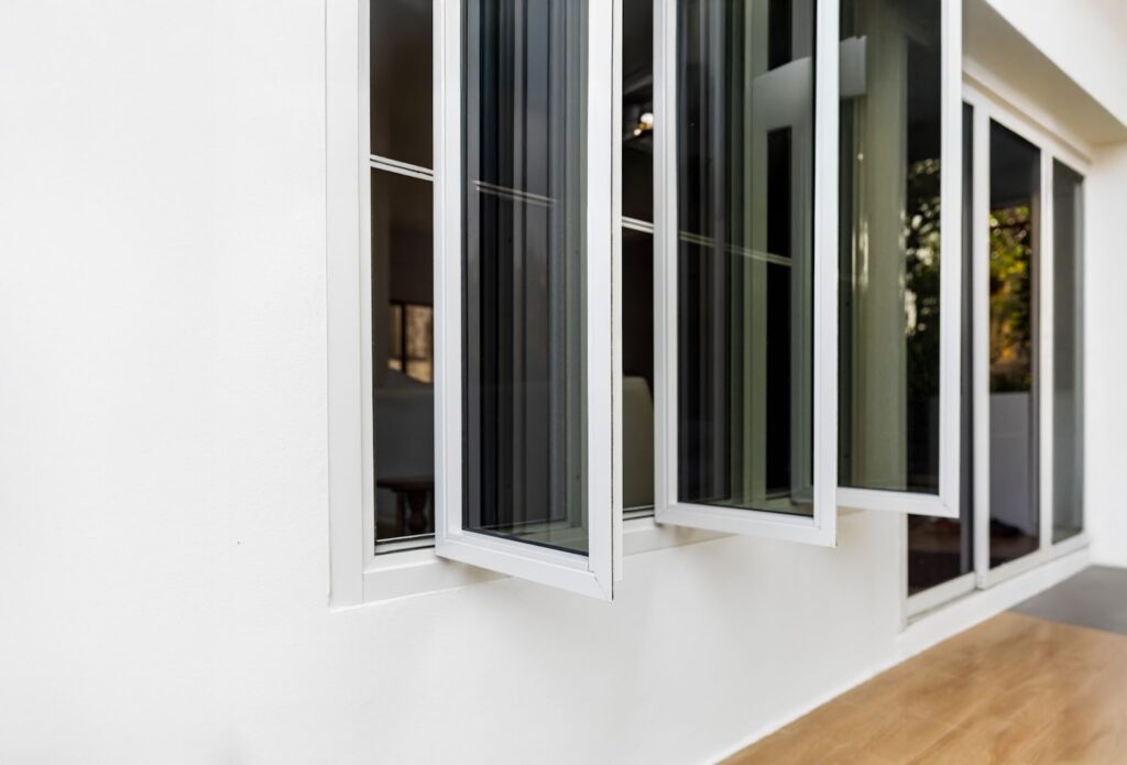 Open casement windows on a modern white wall.