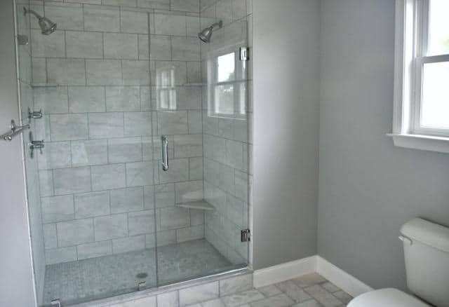 A modern bathroom featuring a glass shower door and a white toilet against neutral-colored walls