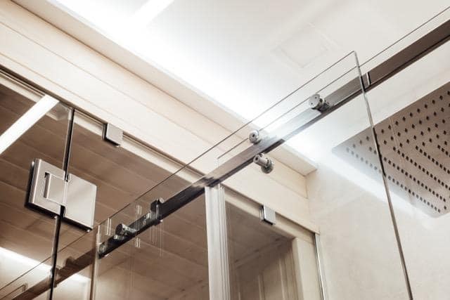 A glass shower door featuring a sleek metal frame showcasing a modern bathroom design