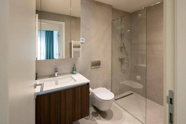 A modern bathroom in a city center apartment featuring a shower, sink, and stylish decor