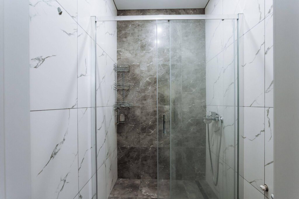 A modern walk in shower with a clear glass door and elegant tile walls showcasing spacious design
