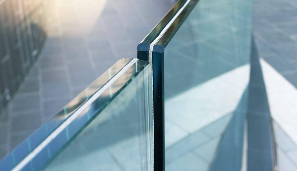 A glass railing featuring a sleek metal top rail providing a modern and elegant barrier
