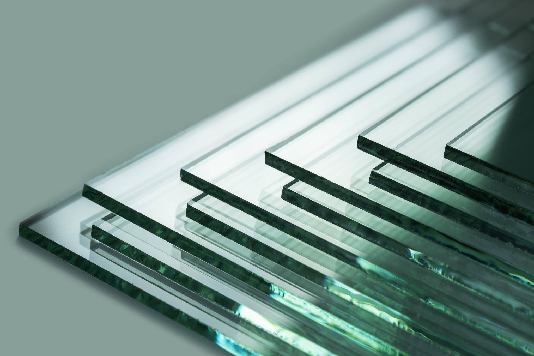 A stack of transparent glass sheets neatly arranged on a wooden table surface